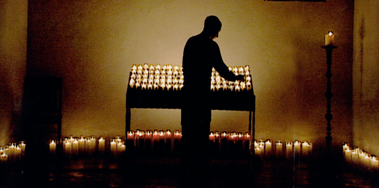 Man lighting candles in a darkened room