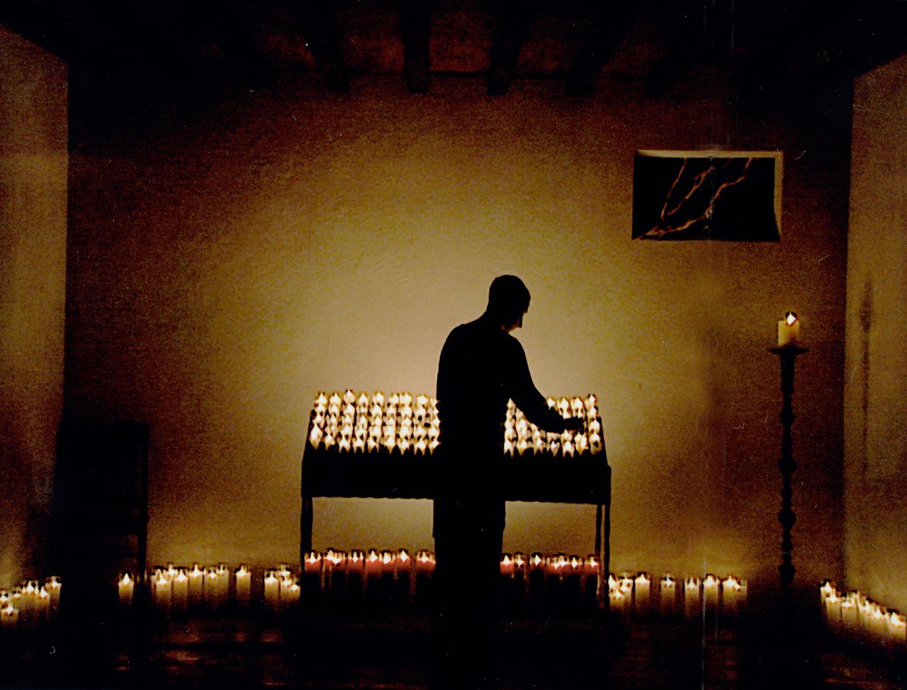 Man in a room lighting candles in silhouette